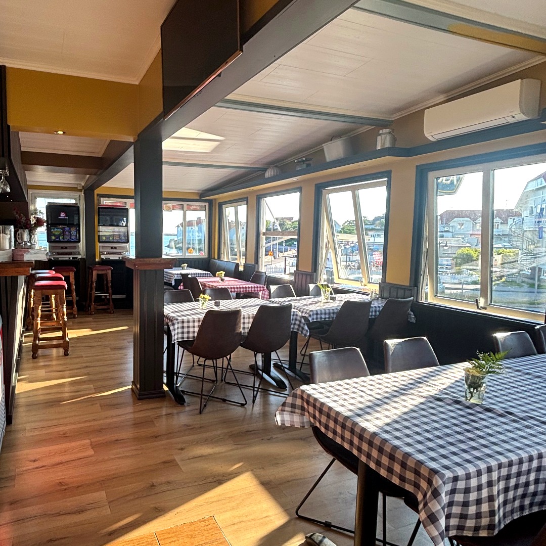 Restaurangens interiör med bar, matsalsbord och havsutsikt